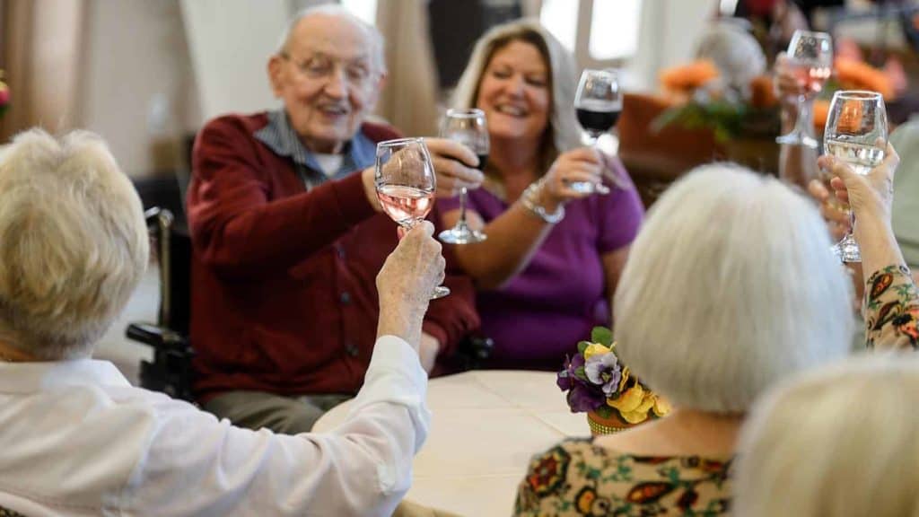 Seniors seated at a table raising wine glasses